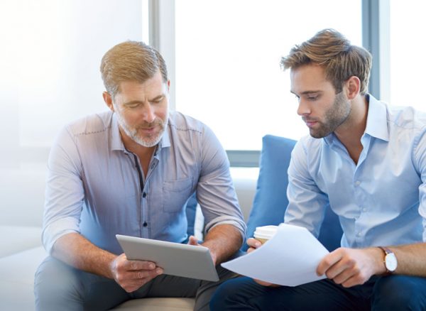 Two business men discussing travel savings while looking at return on investment report
