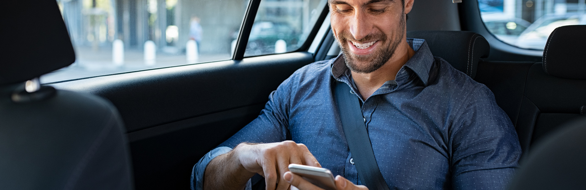 Businessman reading his mobile in a ride share car