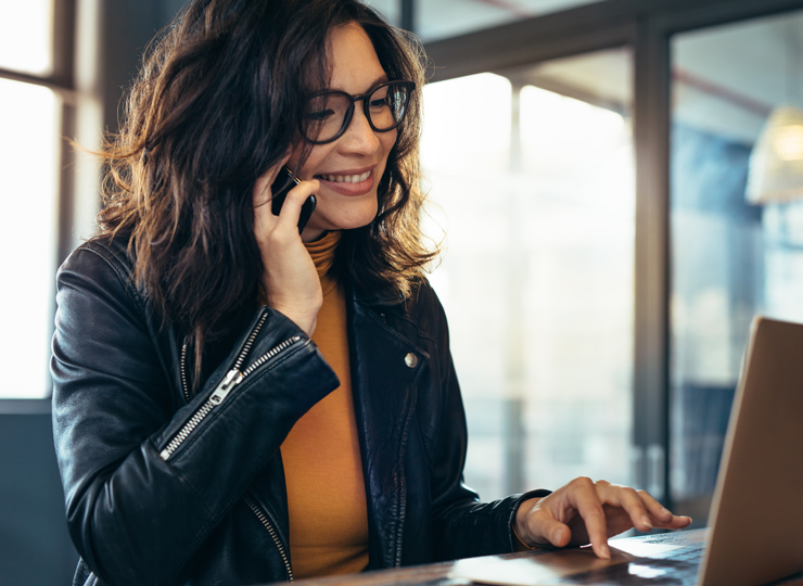 Woman on speaking on phone while working on a laptop