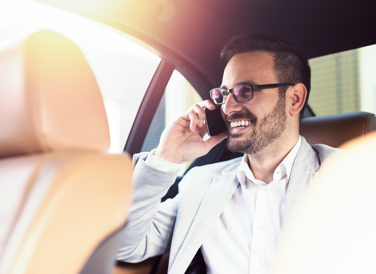 Business traveller talking on phone in back seat of private transfer vehicle