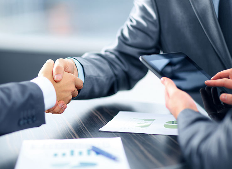 Implementation: Close up view of men's hands shaking over a desk