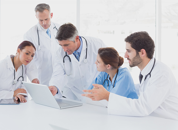 Medical professionals reviewing case studies on laptop